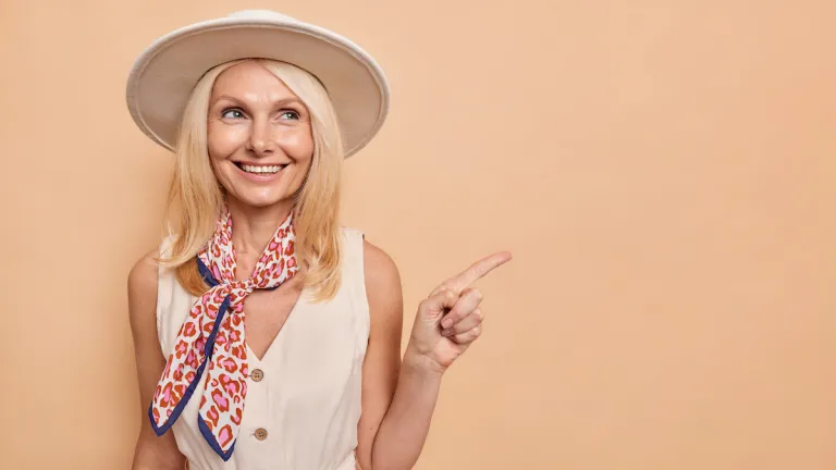 happy middle aged woman beige dress scarf sun hat | MercerOnline