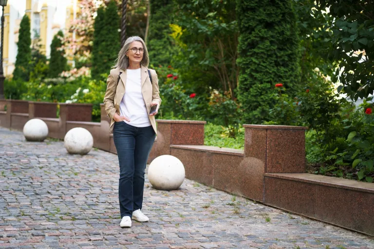 mature woman in jeans and blazer walking down cobblestone street | MercerOnline