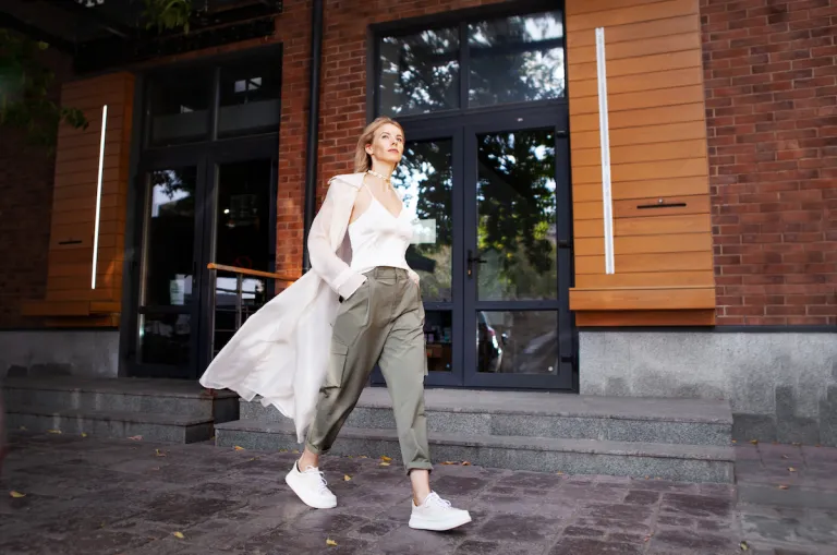 stylish woman walking on city sidewalk wearing white tank green cargo pants | MercerOnline