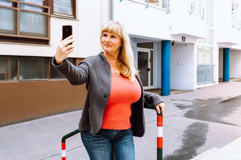 woman on city street taking selfie | MercerOnline
