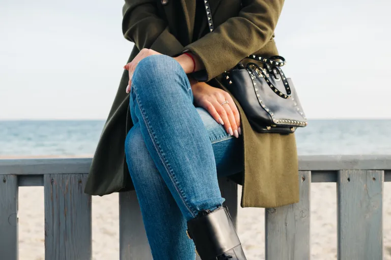 woman sitting near beach wearing olive green jacket and jeans 1 | MercerOnline