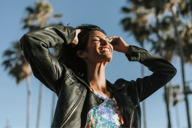 woman smiling in leather jacket near palm trees | MercerOnline