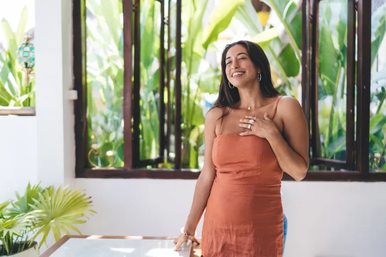 woman smiling orange dress in tropical location | MercerOnline